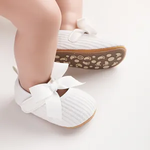 Gros plan de chaussures blanches pour bébé avec de gros nœuds et semelles souples