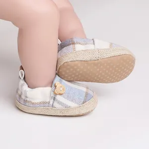 Close-up detail of blue plaid baby walker shoes featuring bear button and non-slip sole