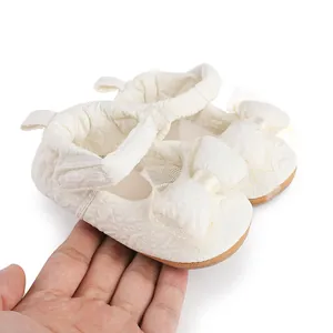 Gros plan sur des chaussures de marche pour bébé crème avec un grand nœud en dentelle.