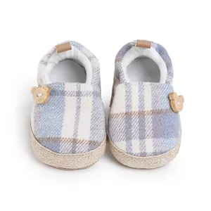 Detalle de zapatos de bebé a cuadros con forro de felpa y lindos botones decorativos de oso.