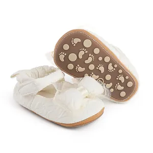 Vue détaillée de la semelle antidérapante et du nœud en dentelle sur chaussons bébé