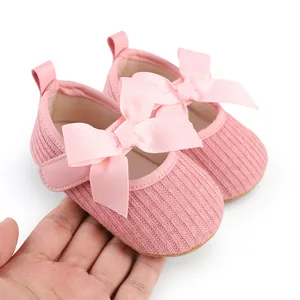 Gros plan de chaussures roses pour bébé fille avec texture tricotée et grands nœuds ruban