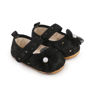 Detailaufnahme schwarzer Baby-Prinzessinenschuhe mit Spitze und Perlenblumen-Dekor.