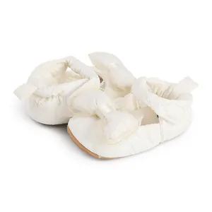 Détail rapproché de chaussures de marche pour bébé crème avec un grand nœud élégant