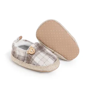 Primer plano de zapatos de cuadros para bebé con suela antideslizante y botón de oso.