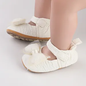 Gros plan sur des chaussures de marche bébé blanches avec tissu gaufré et nœud