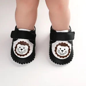 Close-up detail of soft-soled cartoon lion infant walking shoes with velcro strap.