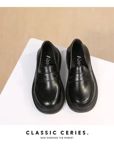 Top view of classic black British style girls' school loafers on white display surface