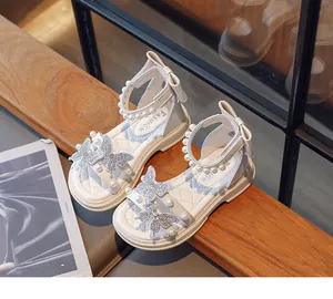 Close-up of white girls' sandals featuring pearl and rhinestone butterfly details
