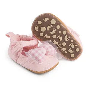 Vue détaillée de chaussures de marche roses pour bébé avec nœud vichy et semelle antidérapante