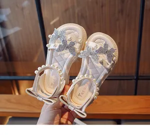 Detailed view of cream girls' sandals with pearl straps and rhinestone butterflies