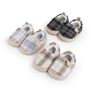 Detalle de zapatos de bebé a cuadros con botones de oso y suelas tejidas