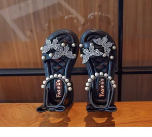 Detail view of black girls' sandals with pearl straps and rhinestone butterfly accents