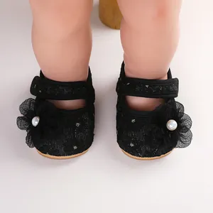 Nahaufnahme eleganter schwarzer Baby-Prinzessinenschuhe mit Spitzenblumen an den Füßen
