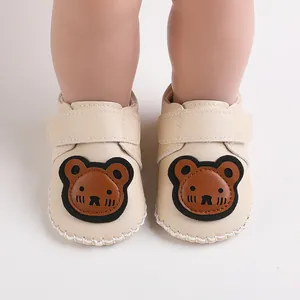 Nahaufnahme von beigen Baby-Lauflernschuhen mit einem niedlichen braunen Bären-Patch