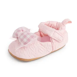 Vue détaillée de chaussure de marche rose pour bébé avec un joli nœud à carreaux
