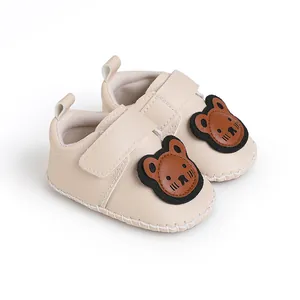 Detailansicht beige Baby-Lauflernschuhe mit niedlichen Bären-Aufnähern und weichen Sohlen.