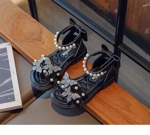 Detailed view of elegant girls' black sandals featuring pearls and butterfly rhinestones.