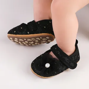 Detailansicht eleganter schwarzer Baby-Prinzessin-Schuhe mit Perlen- und Blumenakzenten.