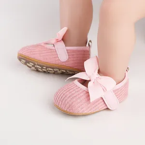 Gros plan de chaussures de fête roses pour bébé fille avec un grand nœud et texture côtelée