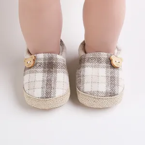 Detalle de zapatos para bebé con estampado de cuadros, botones de oso de madera y suela tejida