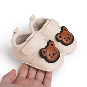 Detailansicht weicher beige Baby-Lauflernschuhe mit süßem Bären-Cartoon-Design.