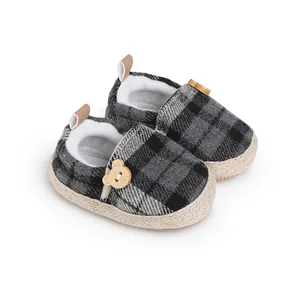 Primer plano de zapatos de bebé a cuadros con forro de felpa suave y botón de oso lindo.