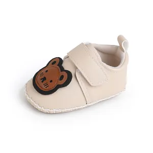 Nahaufnahme von beigen Baby-Lauflernschuh mit einem niedlichen Bären-Aufnäher