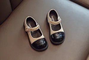 Elegante beige und schwarze Mädchen Mary Janes mit Goldkette und Perlendetail