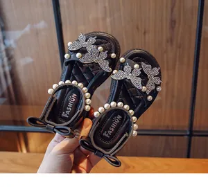 Detail of girl's black sandals featuring rhinestone butterflies and pearl accents
