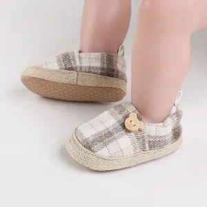 Detalle de los zapatos de bebé a cuadros con un lindo botón decorativo de madera de oso