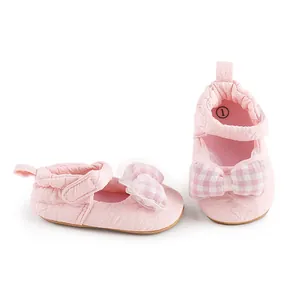 Vue détaillée de chaussures de bébé roses avec un nœud à carreaux et des finitions en dentelle