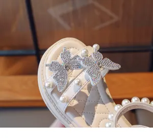 Close-up of sparkling rhinestone butterfly and pearl details on a girl's sandal.