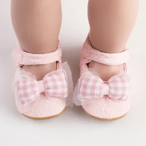 Détail rapproché de chaussures de bébé roses avec un joli nœud à carreaux et dentelle