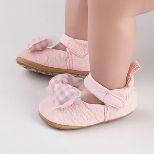 Gros plan de chaussures de bébé roses avec un nœud à carreaux et des détails en dentelle mesh