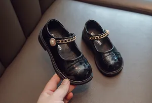 Detail der schwarzen Lackleder-Mary Janes für Mädchen mit Goldkette und Perlenschnalle.