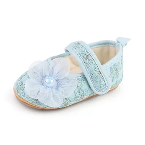 Nahaufnahme von hellblauen Baby-Prinzessin-Schuhen mit Tüllblume und kleiner Perle
