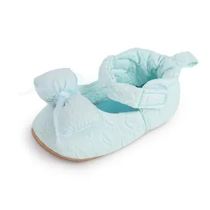 Détail d'une chaussure de bébé bleu clair avec un nœud en maille et un tissu texturé.