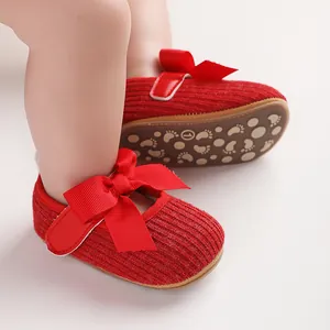 Gros plan sur des chaussures rouges pour bébé avec un grand nœud et une texture douce.