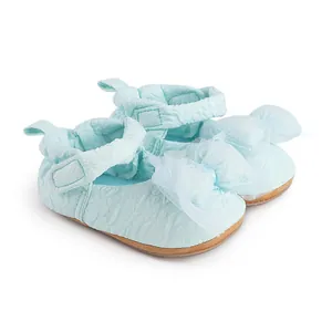 Détail de chaussures de marche bleues pour bébé avec nœud en maille et tissu texturé.