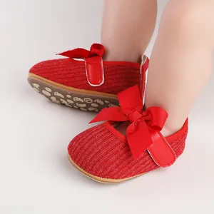 Gros plan de chaussures tricotées rouges pour bébé avec grand nœud et semelle souple