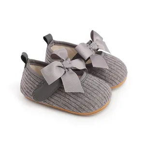 Vue détaillée de chaussures de bébé en tricot gris avec d'élégants nœuds en satin