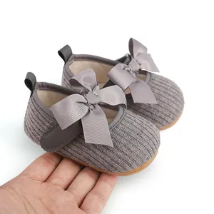 Vue détaillée de chaussures de bébé grises à côtes avec un grand nœud en ruban.