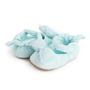 Vue détaillée de chaussures de marche bébé vert menthe avec un nœud en dentelle et texture.