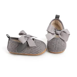 Détail rapproché des chaussures de marche grises pour bébé fille avec nœud élégant.