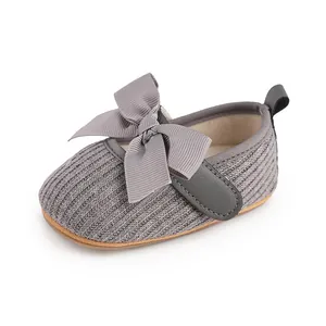 Détail d'une chaussure de marche bébé en tricot gris avec grand nœud déco.