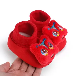 Dettaglio delle scarpine rosse festive per neonati con decorazione in peluche.