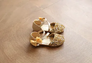 Detailed view of shiny gold sequined children's flat shoes with a delicate bow accent