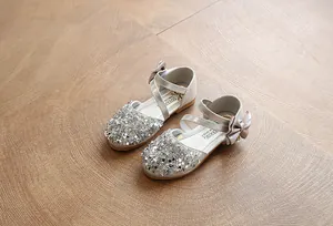 Detailed macro shot of sparkly silver sequins and a satin bow on girls leather dress shoes.