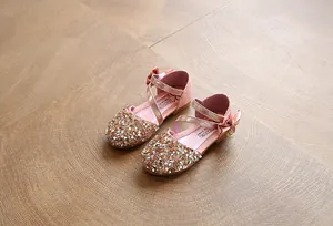Detailed view of pink girls' flat shoes featuring sparkling sequins and a silk bow.